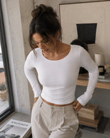 Mujer vistiendo top blanco de manga larga We Love Luana con cuello redondo, diseño ajustado en doble licra elegante.